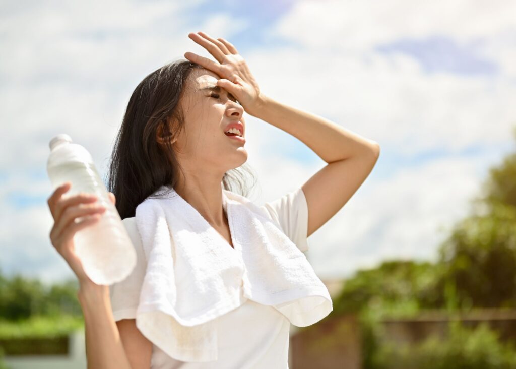 woman in the heat wearing light colored clothing, with a bottle of water