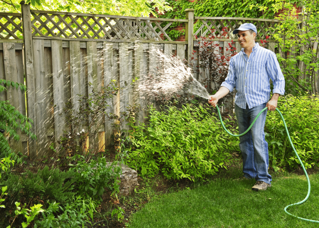 a man watering plants in his yard